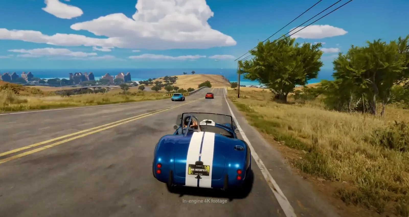 Shelby Cobra numa estrada de colinas douradas com o mar ao fundo